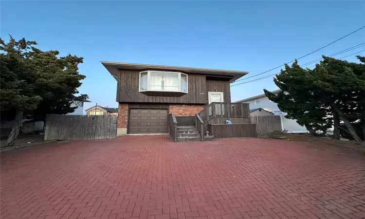 View of front facade with decorative driveway, brick siding, and fence