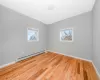 Spare room featuring a baseboard radiator, baseboards, a healthy amount of sunlight, and light wood-style flooring