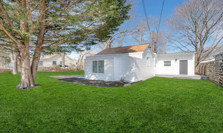 Rear view of house featuring fence and a lawn