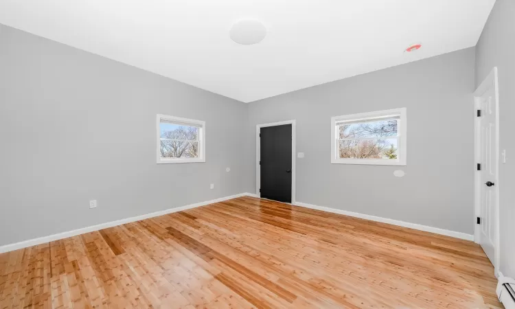 Spare room with baseboards, baseboard heating, and light wood finished floors