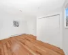 Unfurnished bedroom featuring a baseboard heating unit, light wood-style floors, baseboards, and a closet