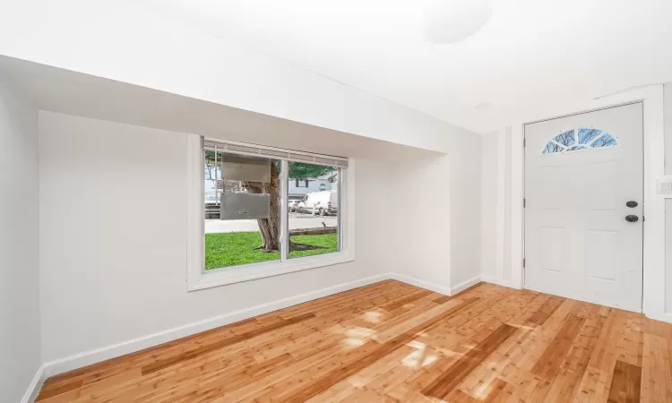 Foyer with baseboards and wood finished floors