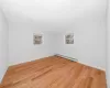 Unfurnished room featuring light wood finished floors, plenty of natural light, baseboards, and baseboard heating