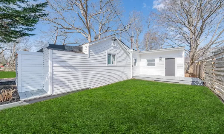 Rear view of house featuring a yard and fence