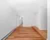 Corridor with a baseboard heating unit, baseboards, and light wood-style floors