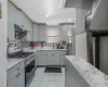 Kitchen featuring a sink, gray cabinetry, light countertops, under cabinet range hood, and appliances with stainless steel finishes