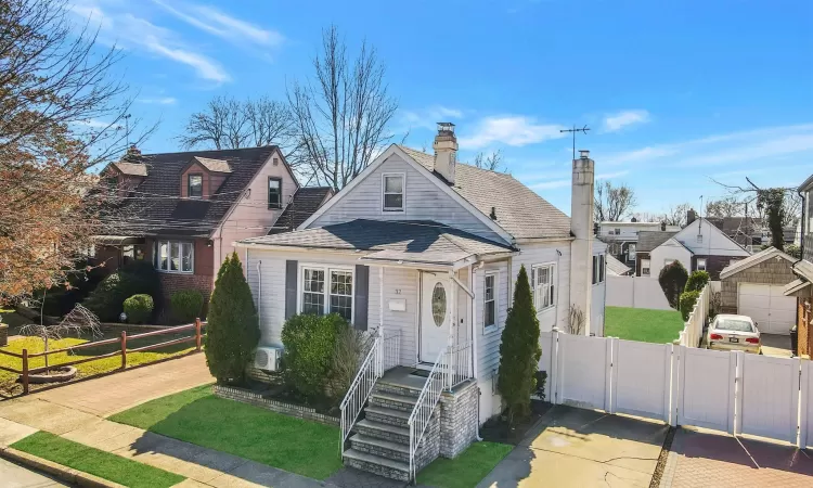 View of front of property with a chimney, fence, roof with shingles, and a gate