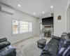 Carpeted living area with recessed lighting, a fireplace, a wall mounted AC, and baseboards