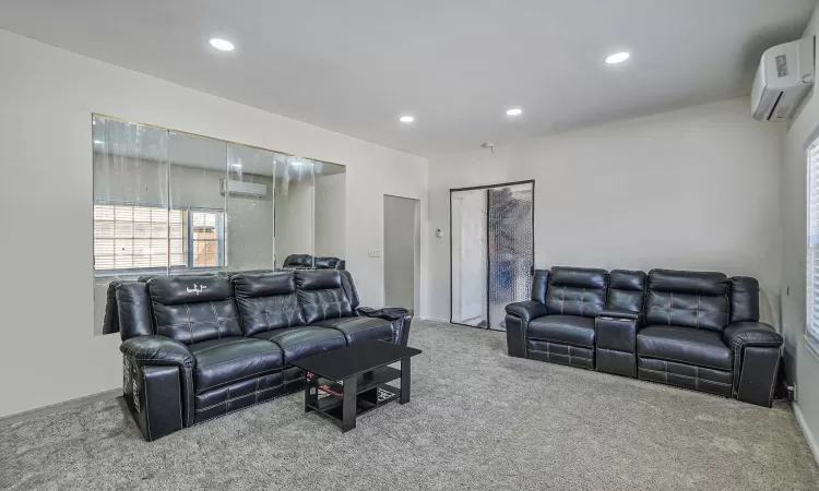 Carpeted living room featuring recessed lighting, baseboards, and a wall mounted AC