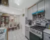 Kitchen featuring tasteful backsplash, gray cabinetry, under cabinet range hood, light tile patterned floors, and stainless steel gas stove