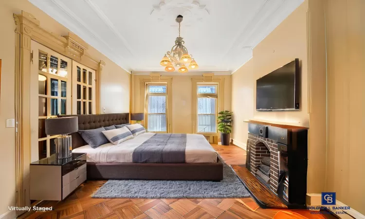 Bedroom with a tray ceiling, baseboards, a chandelier, and ornamental molding