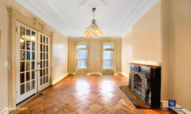 Living area with an inviting chandelier, baseboards, and ornamental molding