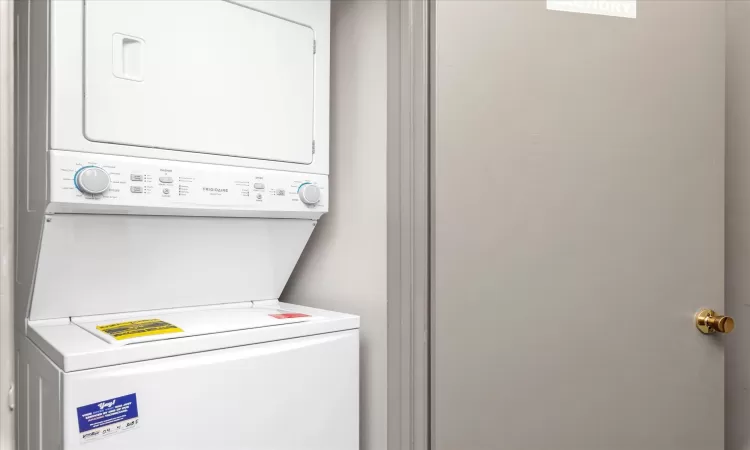 Laundry room featuring laundry area and stacked washer and dryer just outside apt door