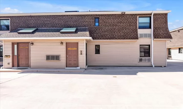 Multi unit property featuring concrete driveway and a shingled roof