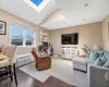 Living area featuring wood finished floors,  vaulted ceiling with skylight, recessed lighting, and an AC wall unit