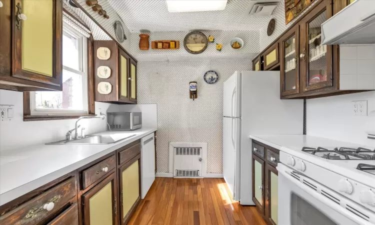 Kitchen with  dark wood-style floors, white appliances, light countertops, and extractor fan