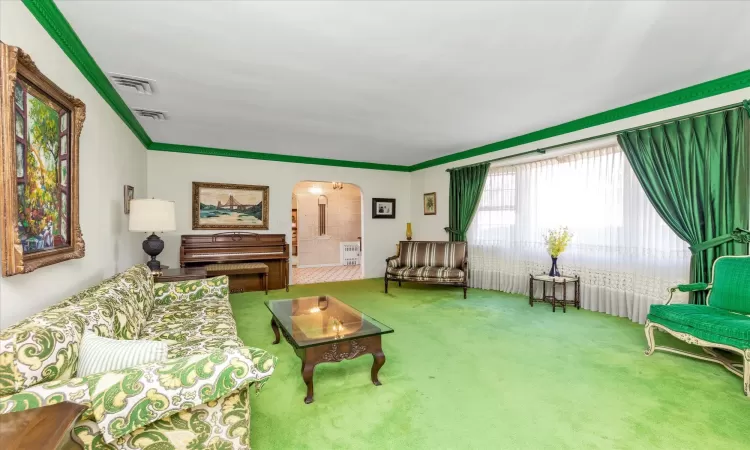 Carpeted living room featuring crown molding,  and arched walkways