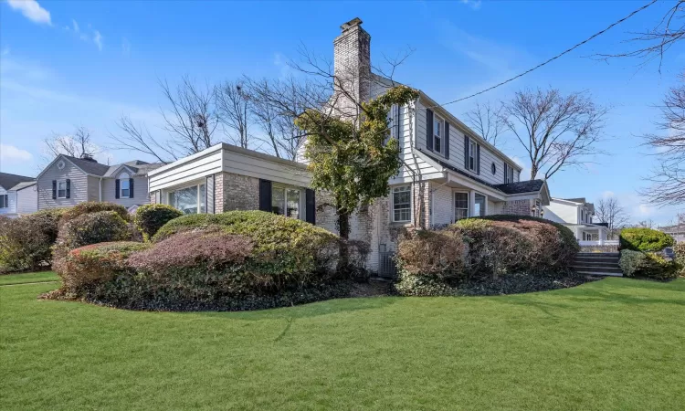 View of side of home featuring a yard, brick siding, and a chimney