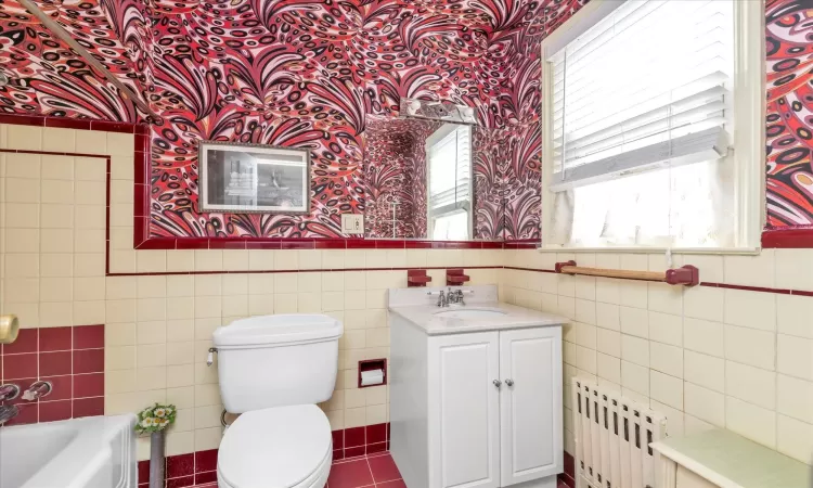 Full bath with  wainscoted wall, toilet, radiator heating unit, and tile walls