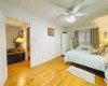 Bedroom featuring light wood-type flooring, baseboards, a ceiling fan, and a wall unit AC