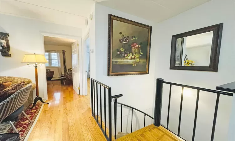 Corridor featuring an upstairs landing and light wood-type flooring