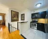 Kitchen with backsplash, stainless steel range with gas stovetop, light wood-style floors, black microwave, and dark cabinets