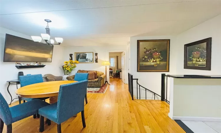 Dining room with baseboards, a notable chandelier, and light wood-style flooring