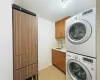 Laundry area with light wood-style flooring, cabinet space, a sink, stacked washer and clothes dryer, and a textured ceiling