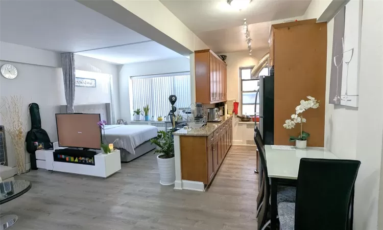 Kitchen featuring open floor plan, light countertops, light wood-style flooring, freestanding refrigerator, and brown cabinetry