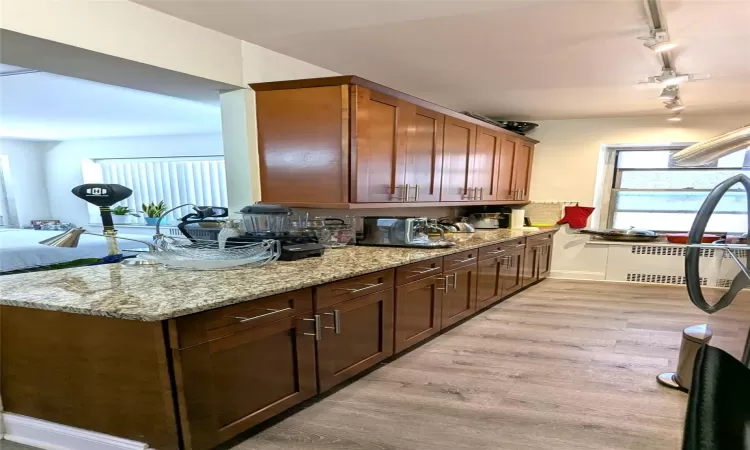 Kitchen with light stone counters, light wood-style flooring, and rail lighting