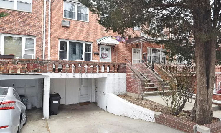 View of property featuring concrete driveway, an AC wall unit, and brick siding