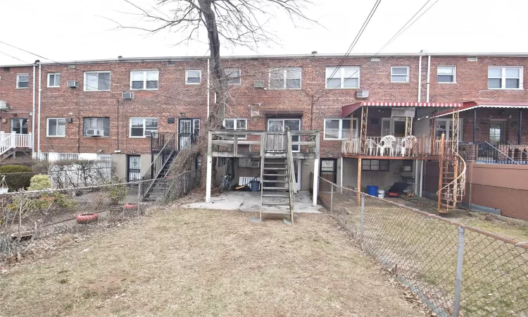 Back of property featuring stairway, brick siding, and fence private yard