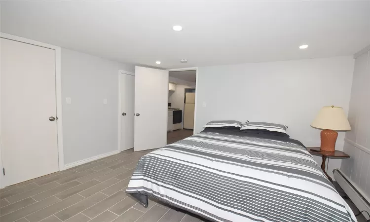 Bedroom with recessed lighting, a baseboard radiator, and wood finished floors