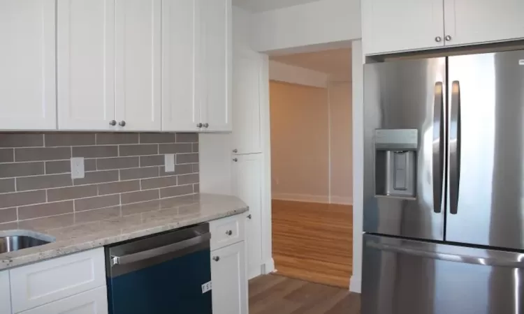 Kitchen featuring backsplash, wood finished floors, white cabinets, stainless steel fridge with ice dispenser, and dishwasher