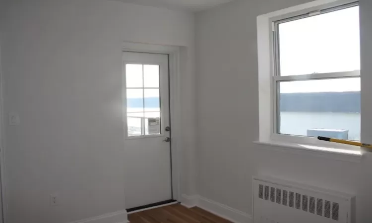 Doorway featuring radiator heating unit, baseboards, and dark wood-style flooring