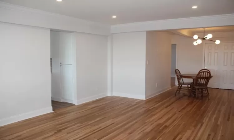 Unfurnished dining area with ornamental molding, baseboards, an inviting chandelier, and wood finished floors