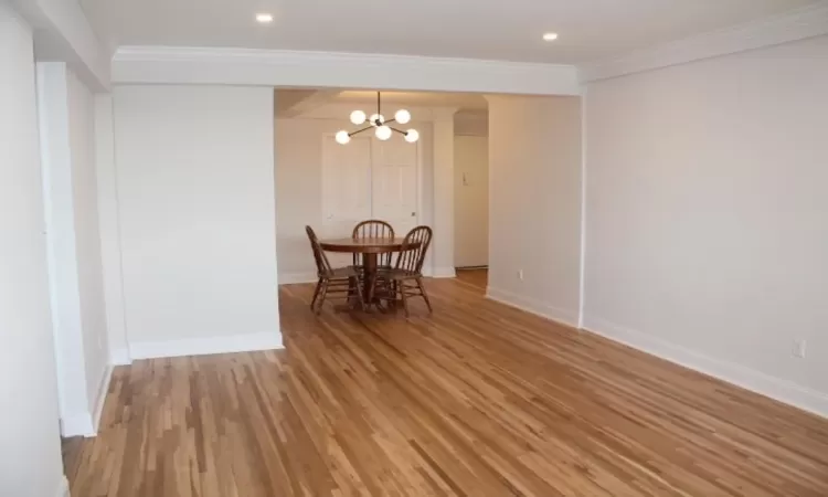 Dining area with baseboards, light wood-style floors, an inviting chandelier, and crown molding