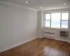 Empty room featuring crown molding, radiator heating unit, baseboards, and a wall mounted air conditioner