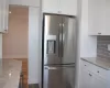 Kitchen with stainless steel fridge, tasteful backsplash, and white cabinetry