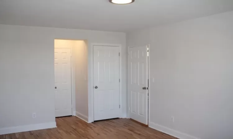 Unfurnished bedroom featuring wood finished floors and baseboards