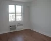 Spare room with baseboards, wood finished floors, radiator heating unit, and a wall unit AC