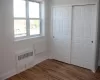 Unfurnished bedroom featuring radiator, wood finished floors, and baseboards