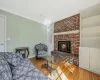 Living room with baseboards, wood-type flooring, a brick fireplace, and ornamental molding