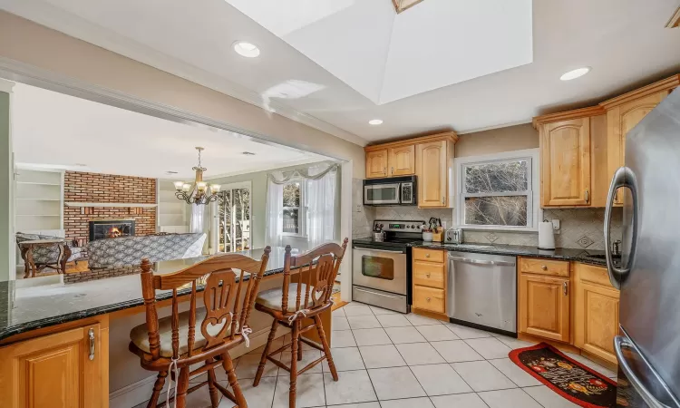 Kitchen with light tile patterned floors, stainless steel appliances, a healthy amount of sunlight, and ornamental molding