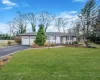 Ranch-style home with a front lawn, an attached garage, driveway, and fence