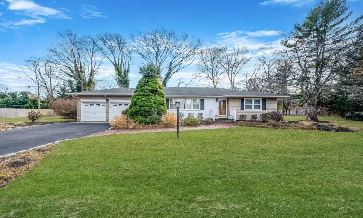 Ranch-style home with a front lawn, an attached garage, driveway, and fence