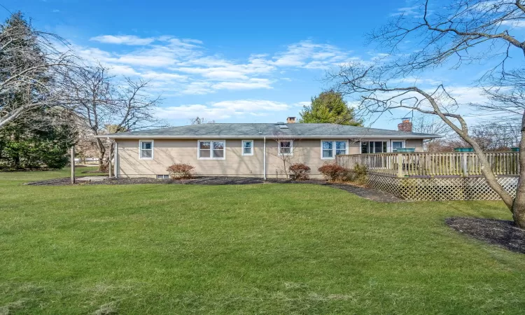 Rear view of house featuring a wooden deck and a lawn