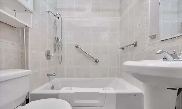 Full bathroom with toilet, a sink, tasteful backsplash, tile walls, and tub / shower combination