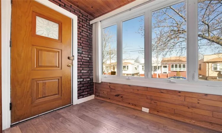 Entryway with a residential view, a healthy amount of sunlight, brick wall, and wood finished floors