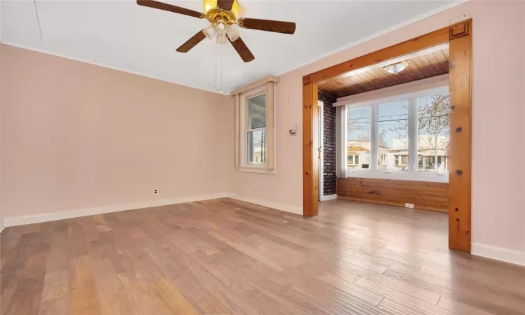 Spare room featuring ceiling fan, baseboards, ornamental molding, and light wood finished floors